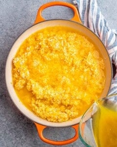 Broth bring poured into yellow rice, simmering away.