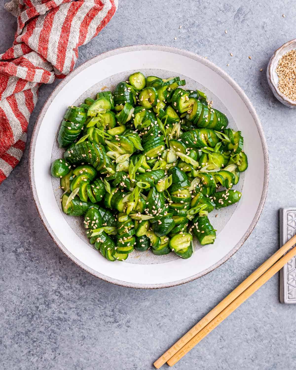 White bowl with spiraled cucumber salad topped with sesame.