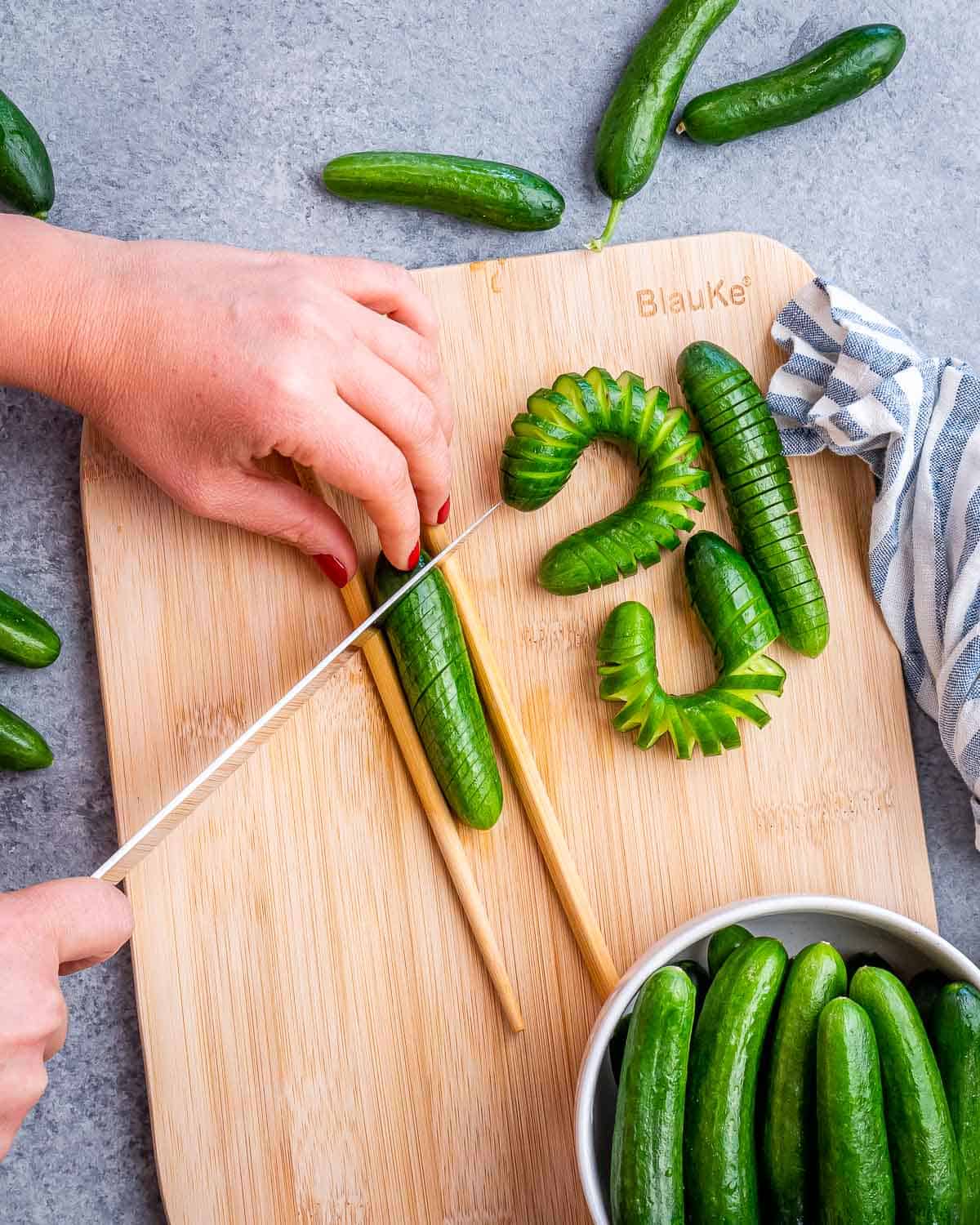 Cutting a mini cucumber between two chopsticks.