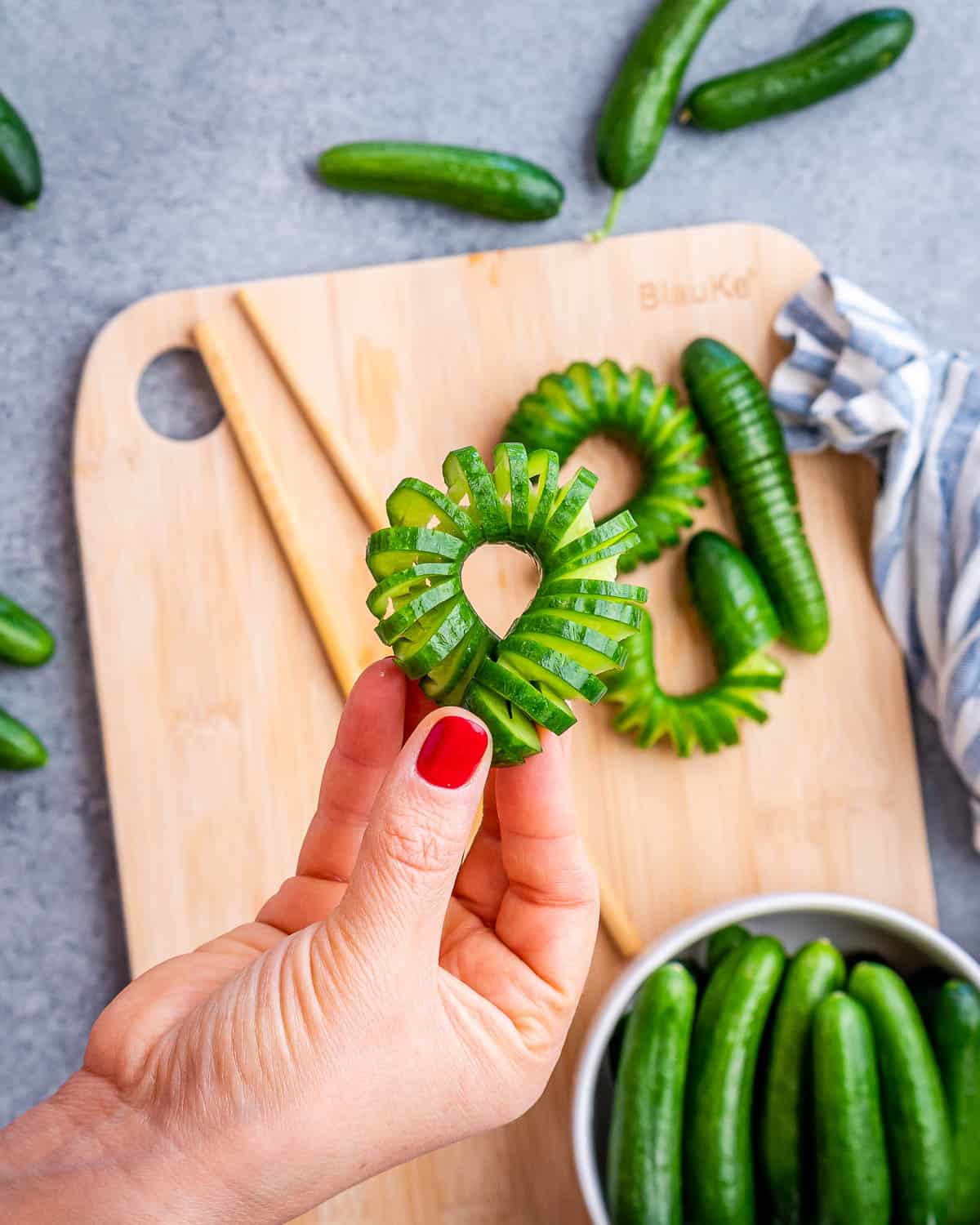 Hand holding a mini cucumber that has slices in it.