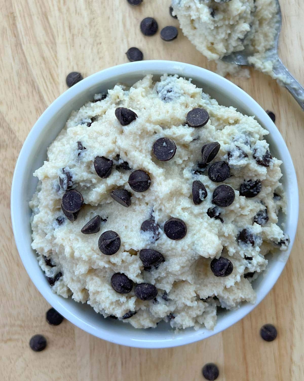 cookie dough in a round white bowl on a light brown cutting board.