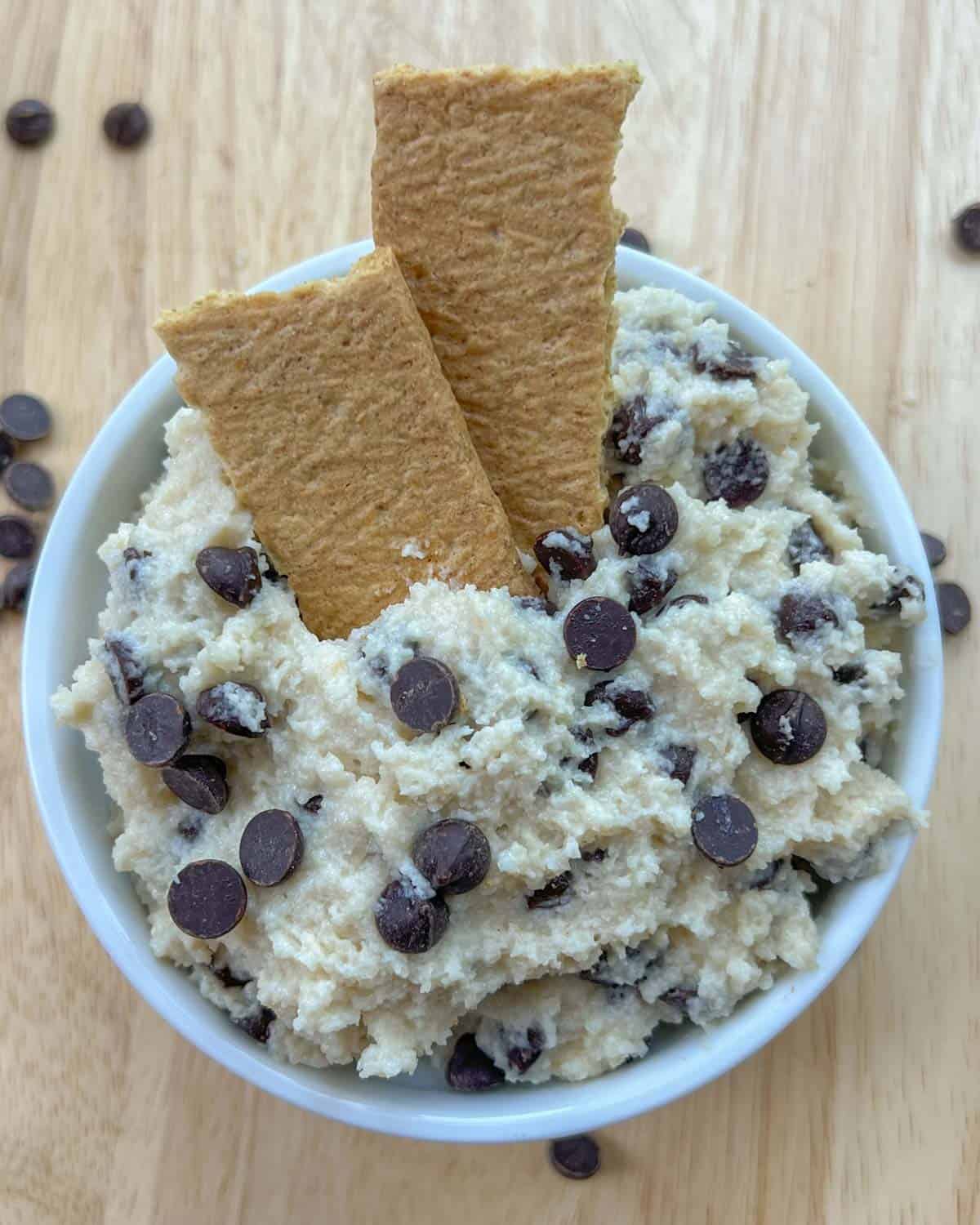 cookie dough in a round bowl with 2 crackers in the cookie dough.