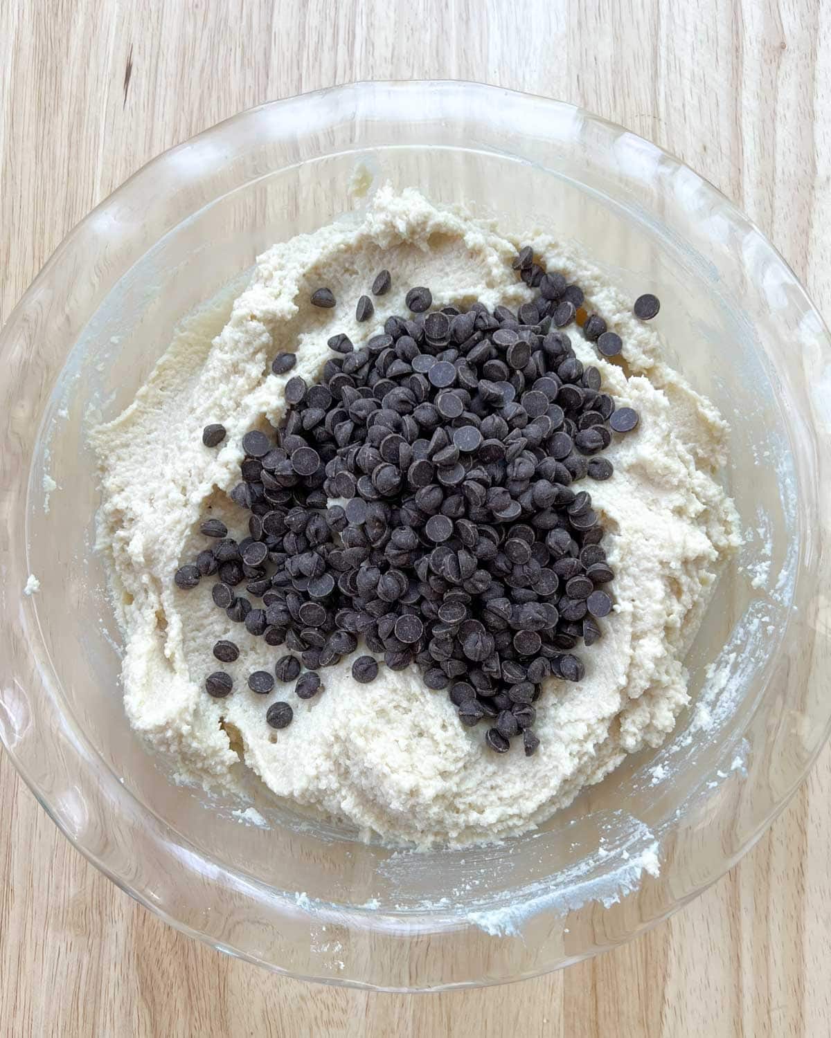 chocolate chips are added over cookie dough in a dish.