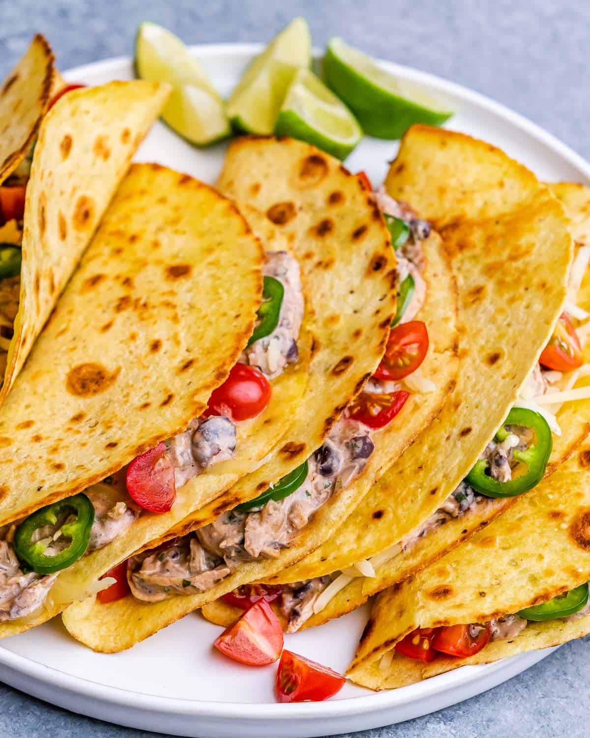 A plate of finished chicken tacos with golden tortillas, colorful toppings, and lime wedges ready to serve.