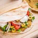 smashed pita sandwich on a wooden board.