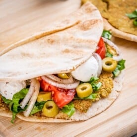 smashed pita sandwich on a wooden board.