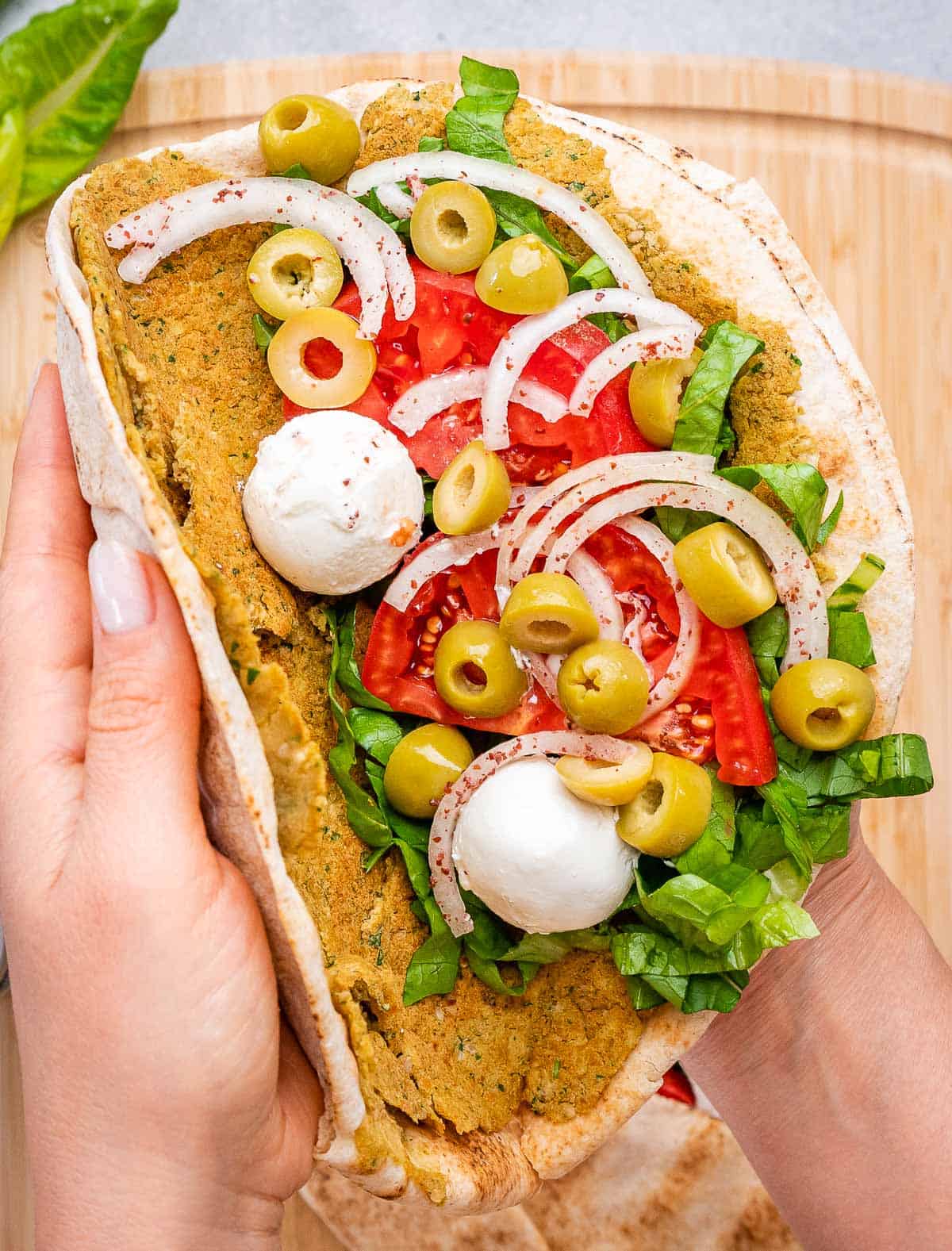 hand folding a falafel smash pita.
