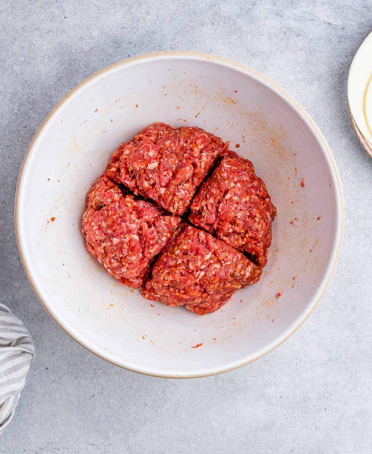 Forming ground beef into a patties on a white plate.