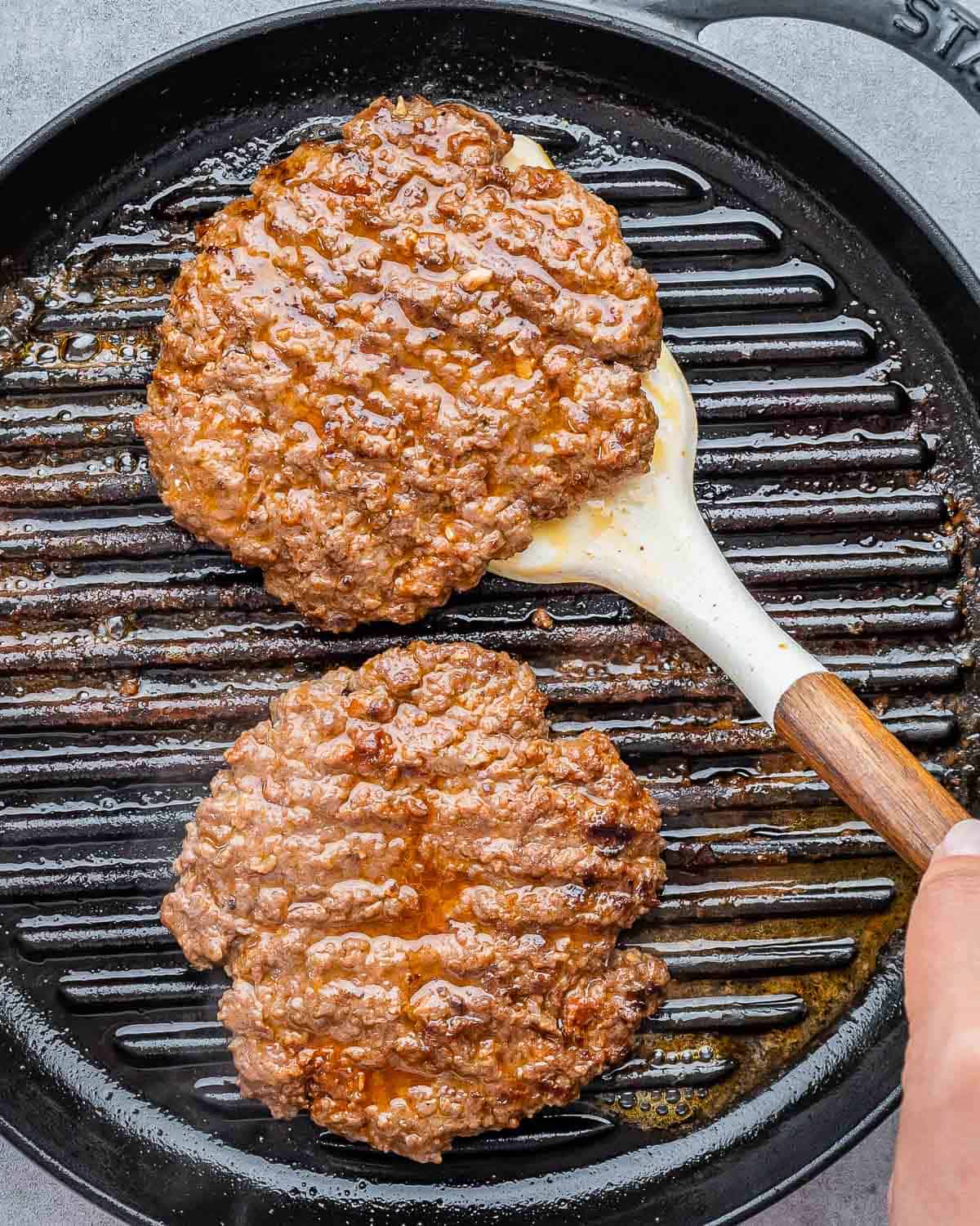 Flipping burger patties on a grill pan.