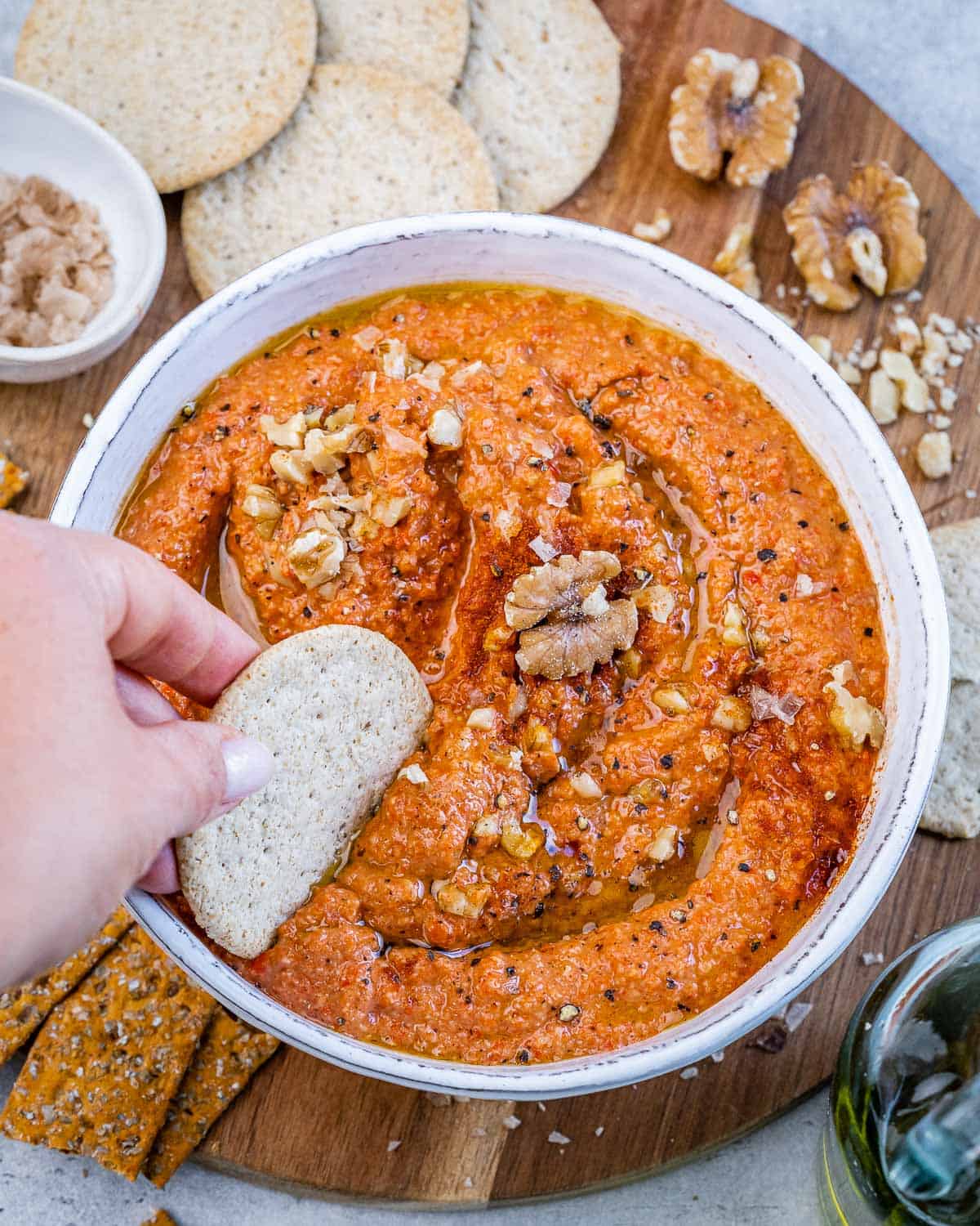 hand dipping a chip in the muhammara dip.