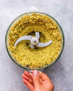 Food processor bowl filled with ground chickpea and herb mixture for making falafel.