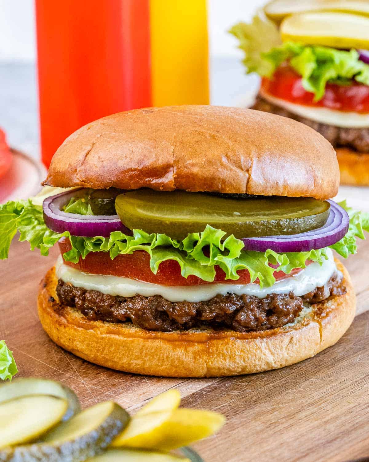 A homemade hamburger with lettuce, tomato, onion and pickles.