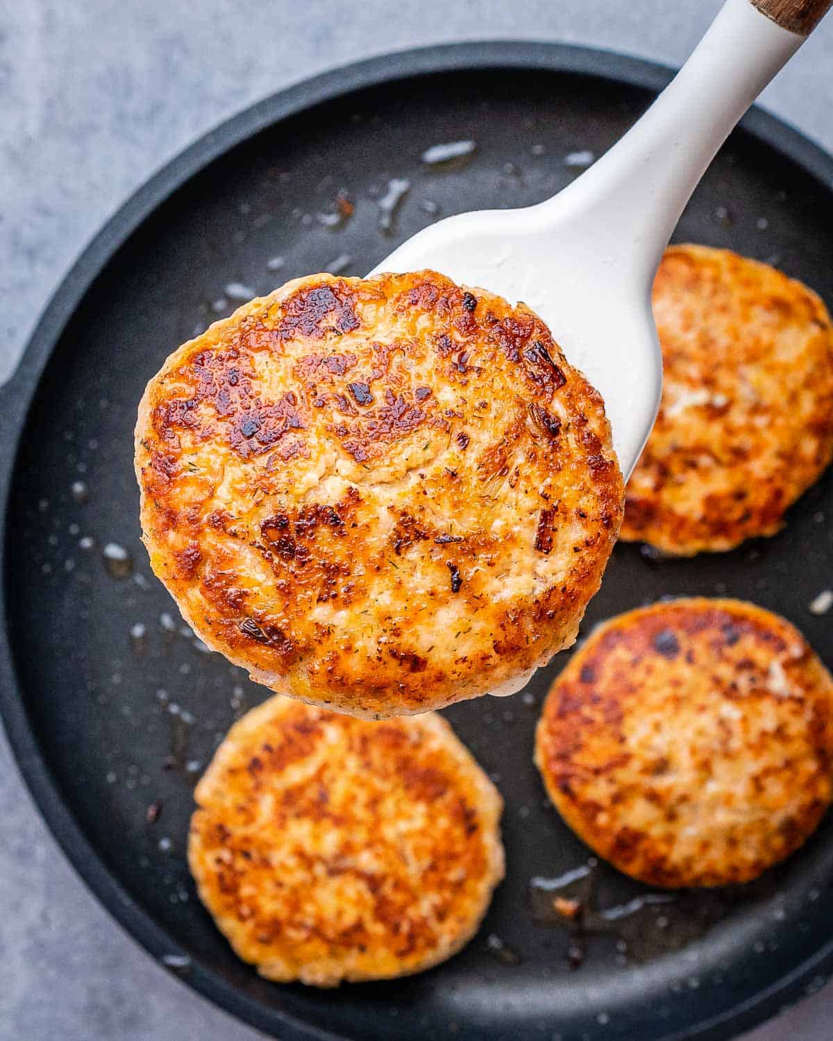 Flipping salmon burgers in a pan.