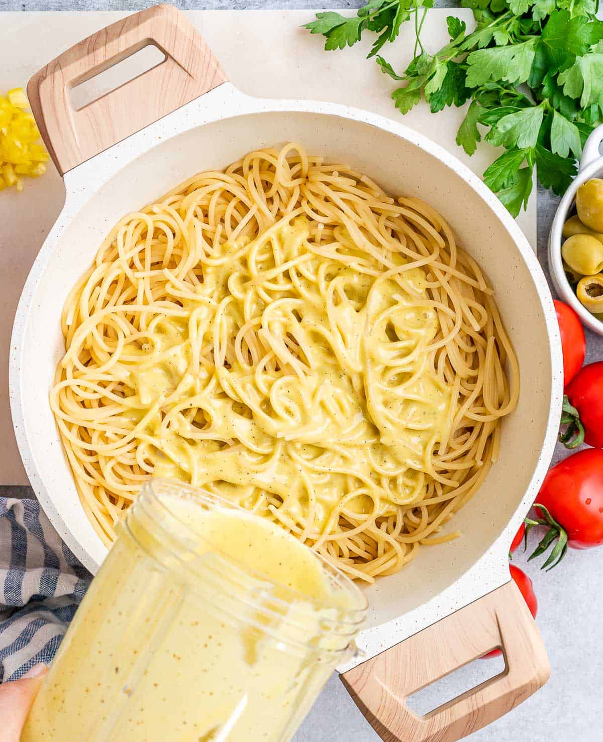 salad dressing being poured over spaghetti.