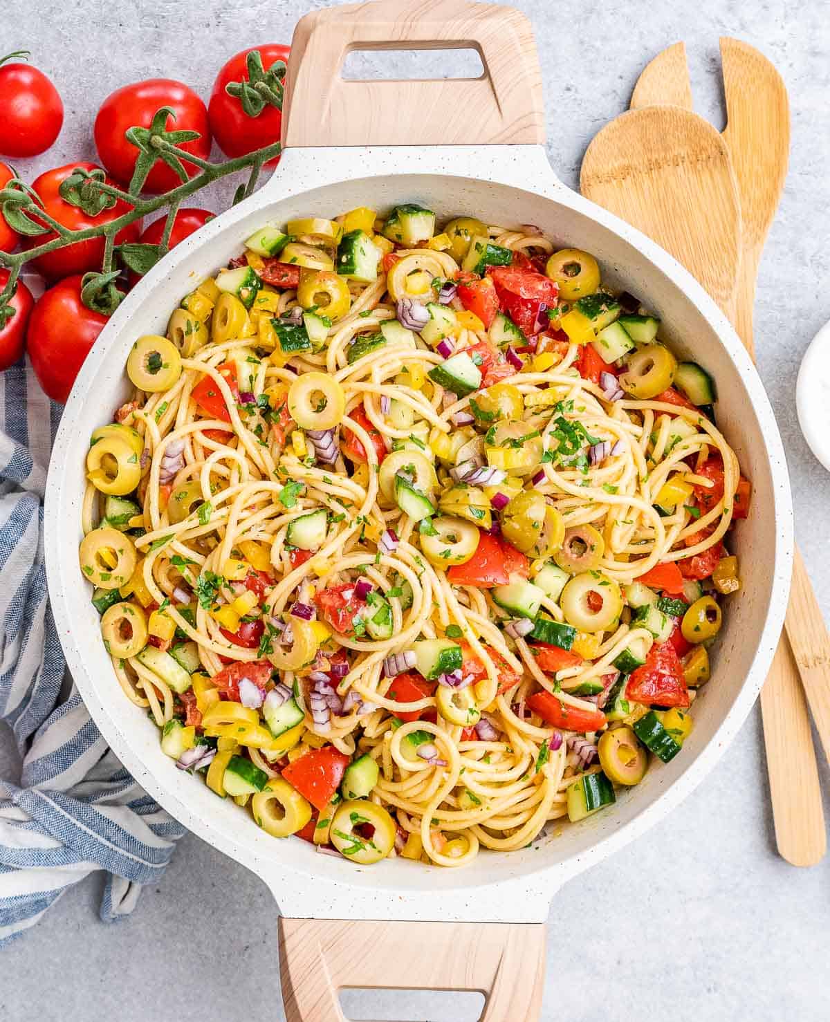 a round white dish that has spaghetti salad with veggies. 