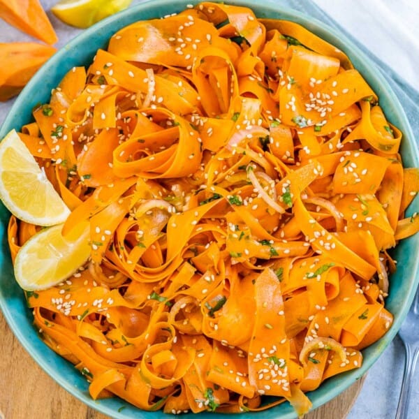 Sliced carrot salad in a round blue bowl.