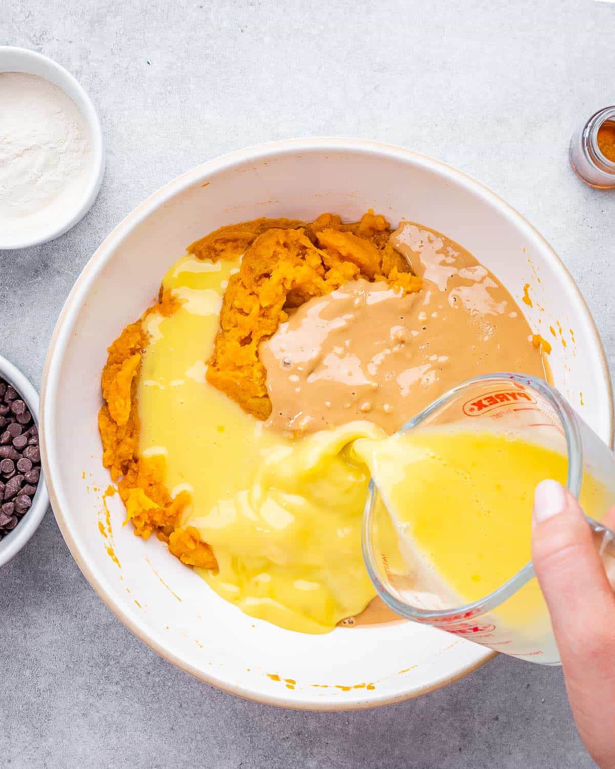 beaten eggs are added over mashed sweet potatoes and peanut butter in a round bowl.