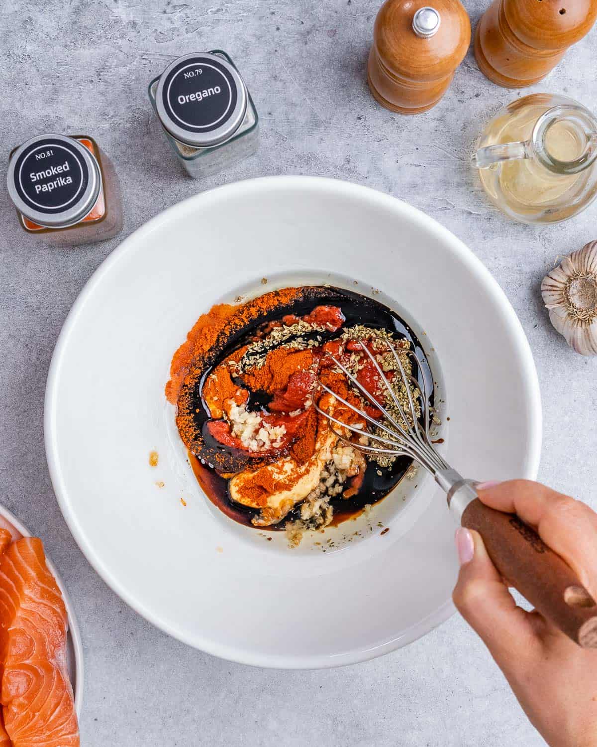 Whisking spices with avocado oil and balsamic glaze in a white bowl.