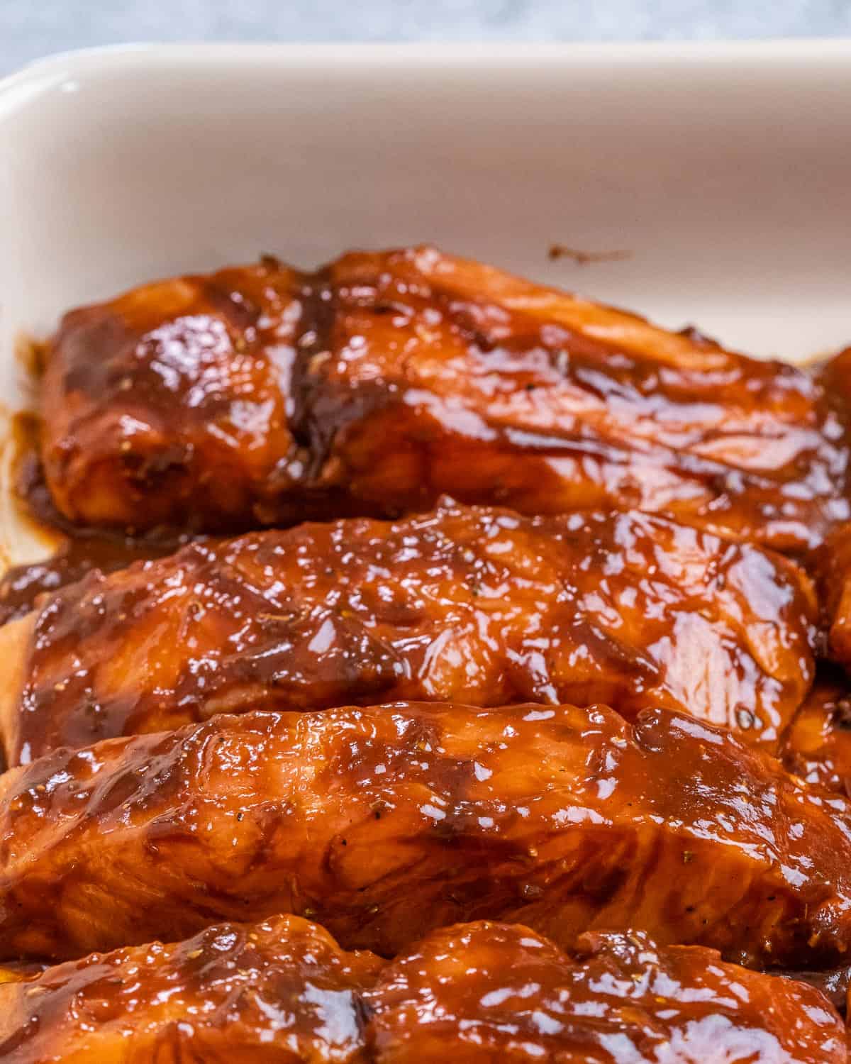 Adding salmon filets to a baking dish.