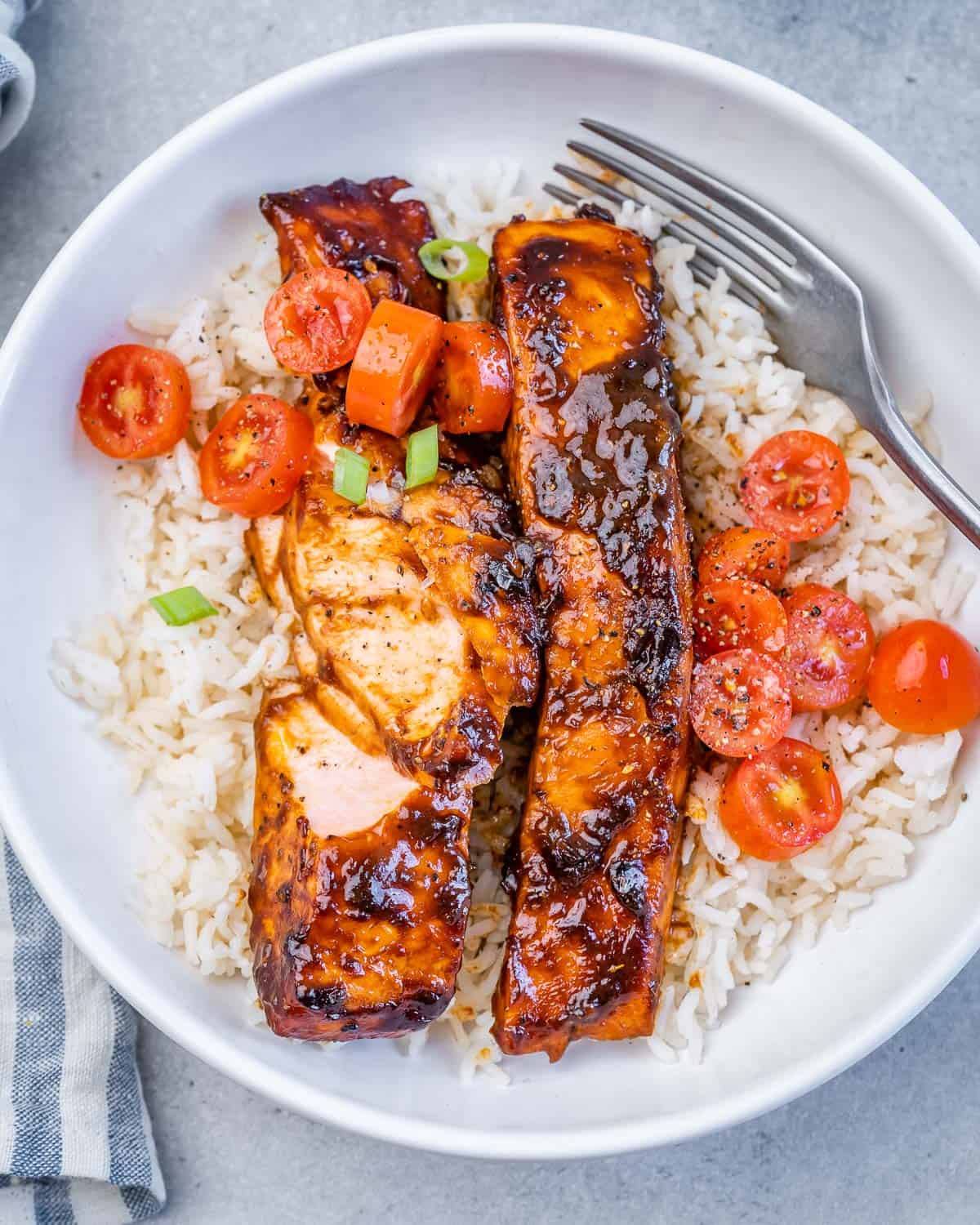 Flaked balsamic glazed salmon in a bowl with rice and cherry tomatoes.