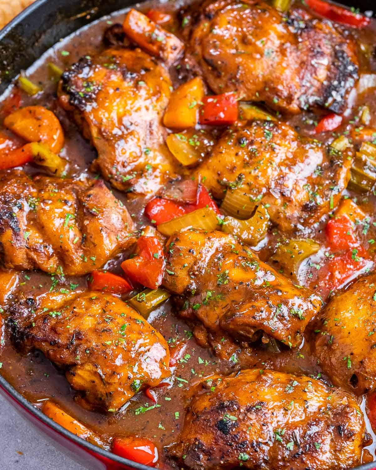 A closeup of brown stew chicken in a skillet.