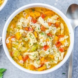 soup with pasta chicken and veggies in a round white bowl.