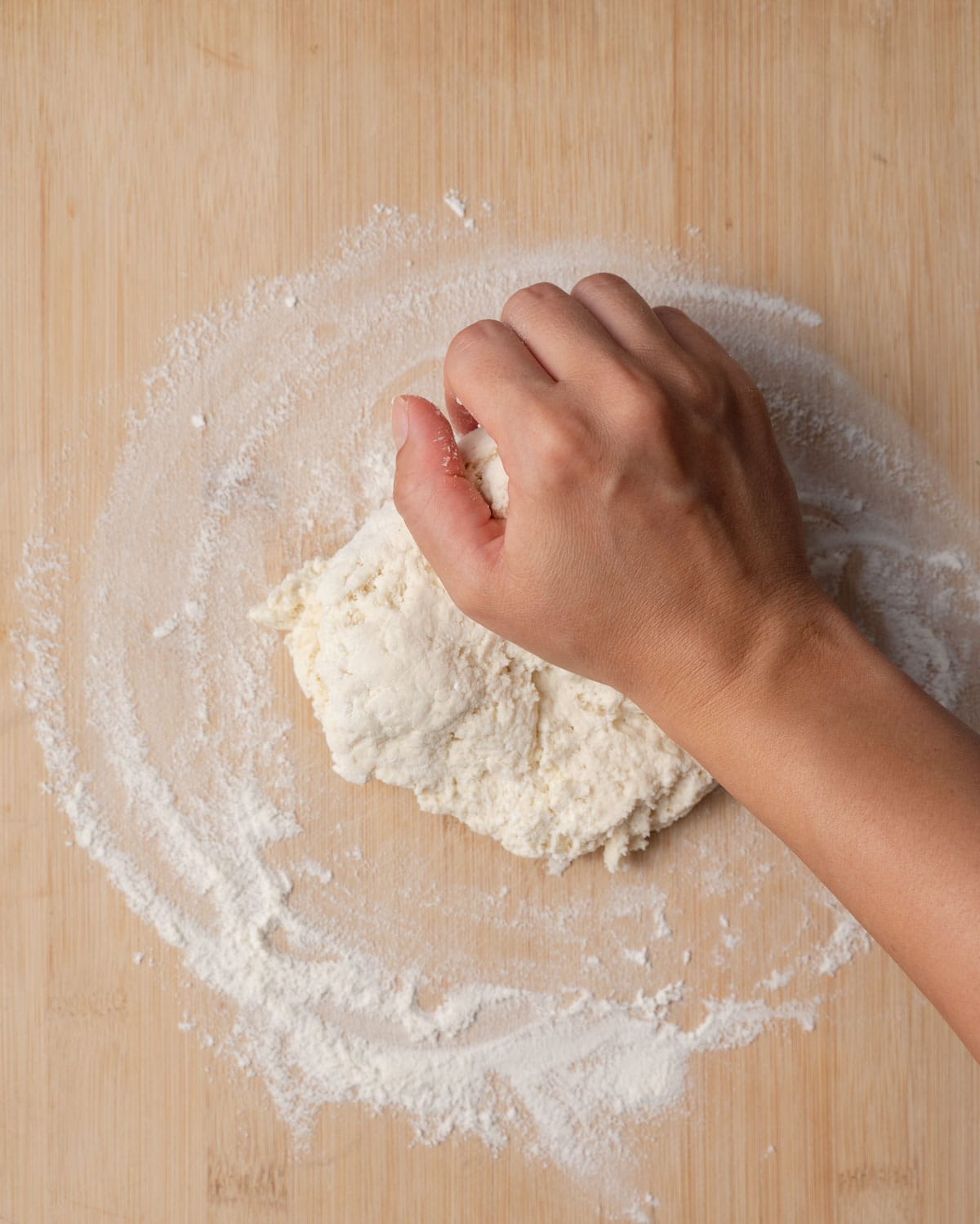 hand kneading dough over a flat surface with flour.