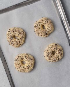 raw bagels added on a sheet pan to be baked.