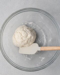 round bread dough with a spatula in a bowl.