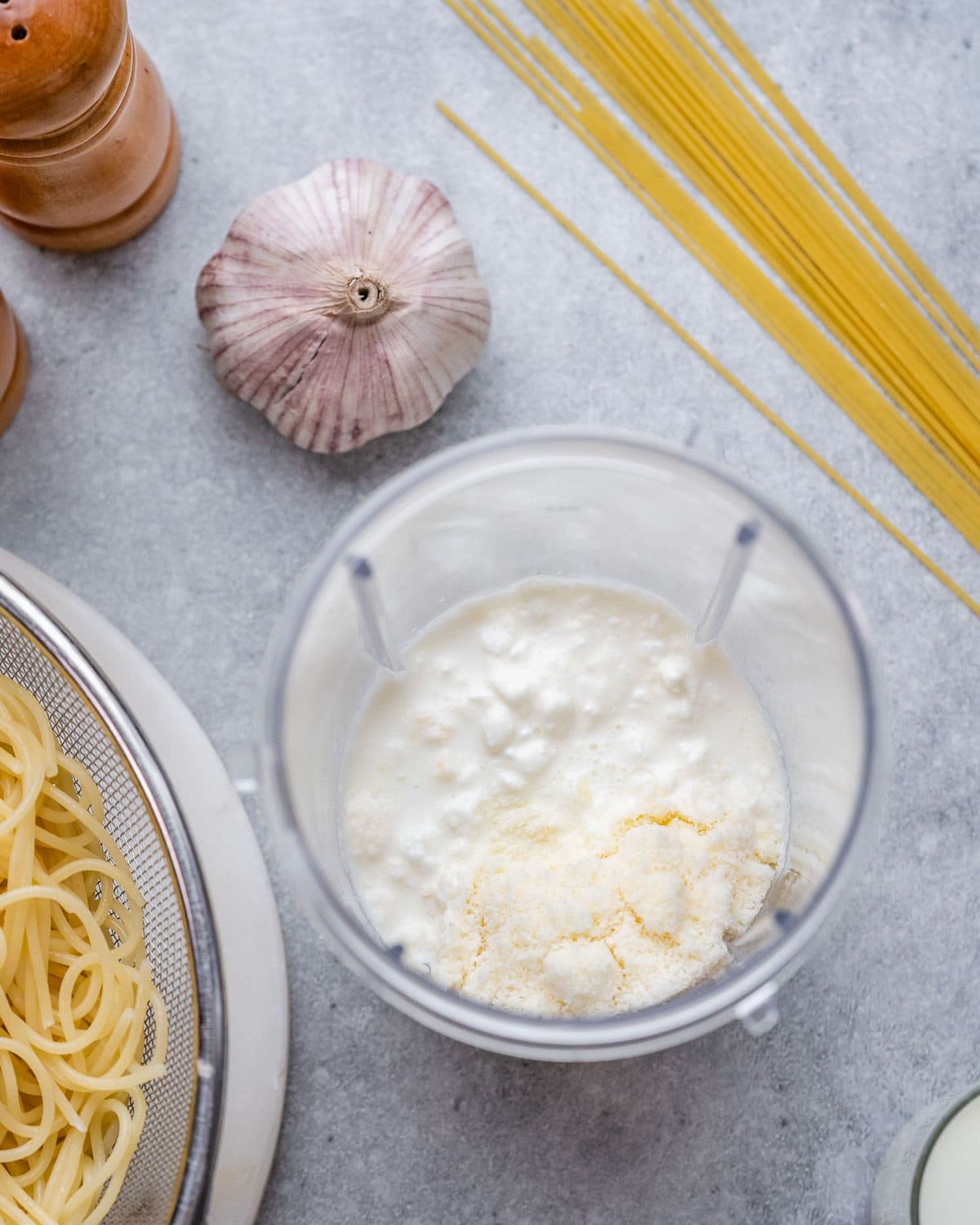 Cottage cheese, milk, and parmesan added to a blender, ready to be blended into a smooth sauce.