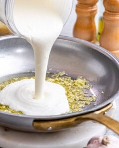 Sauce streaming into the hot skillet, mixing with the garlic and olive oil to begin thickening.