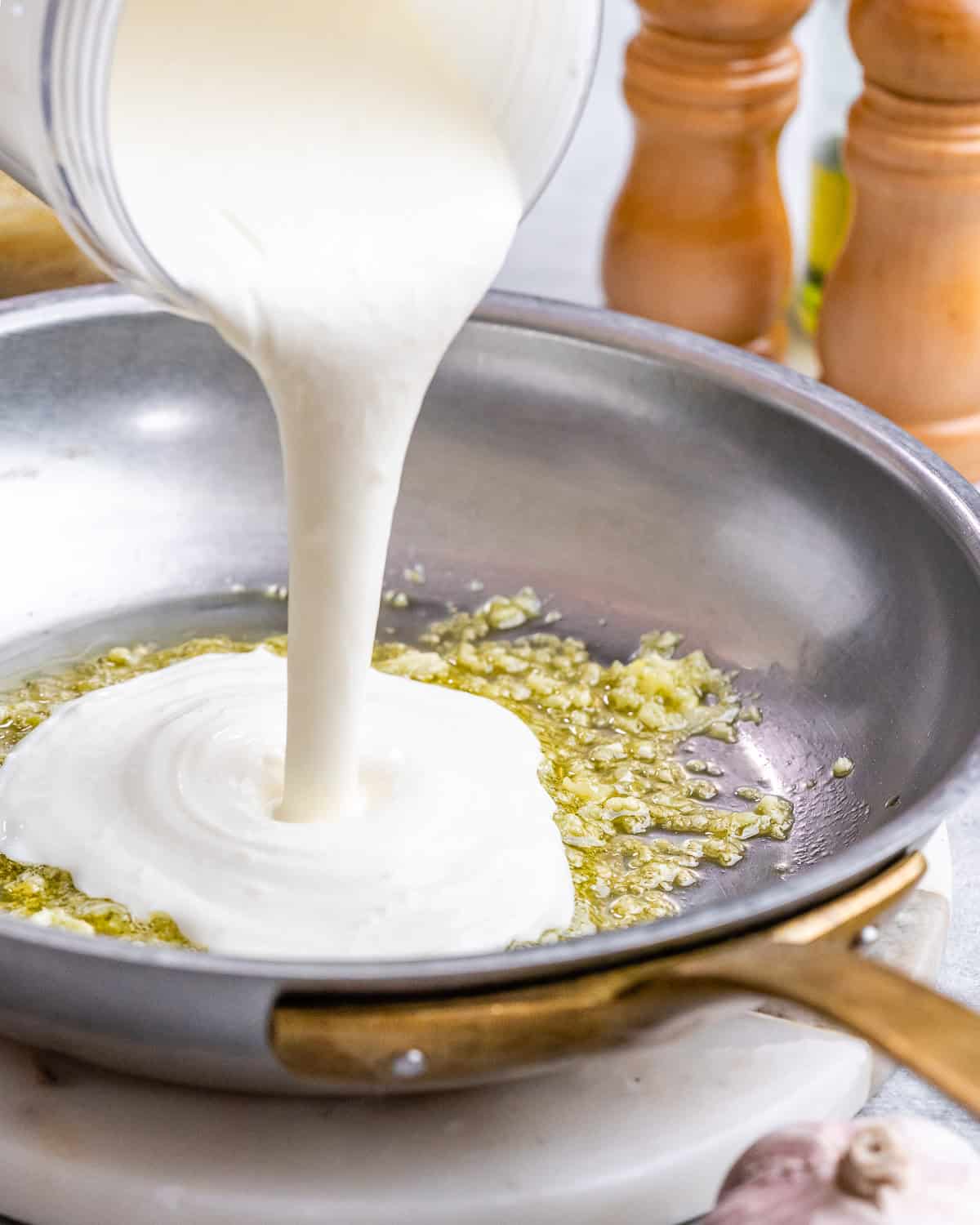 Sauce streaming into the hot skillet, mixing with the garlic and olive oil to begin thickening.