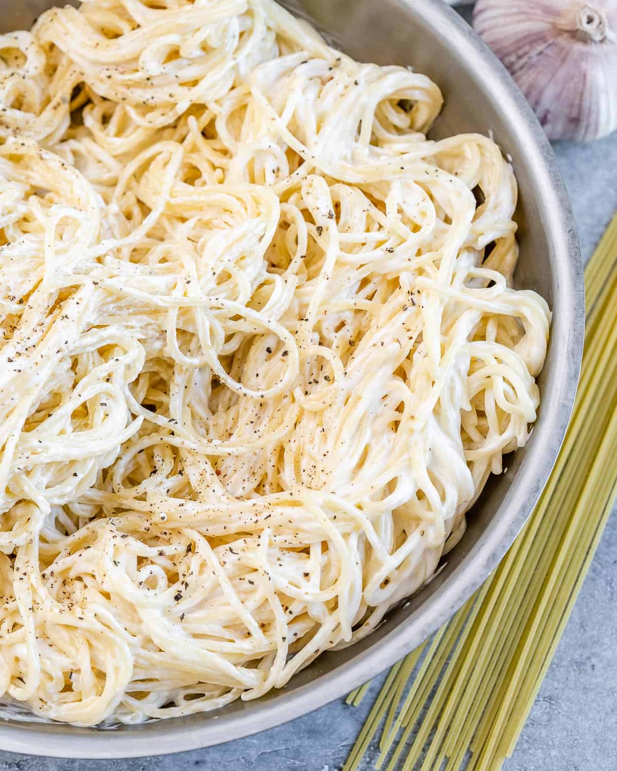 Overhead image of Alfredo spaghetti served in a bowl and topped with grated parmesan cheese.
