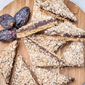 date square bars on a wooden platter with 3 fresh dates next to them.