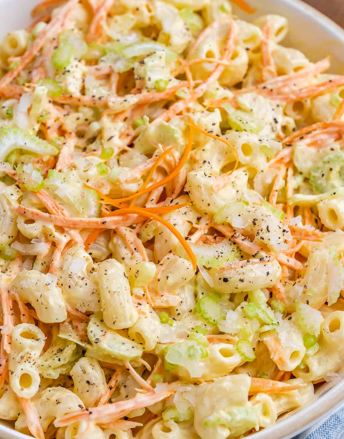 Close-up of the finished Hawaiian mac salad showing creamy pasta mixed with carrots, celery, and black pepper.