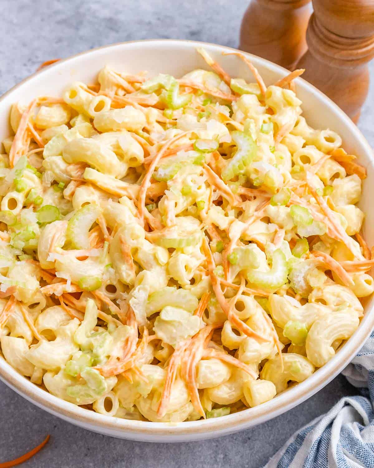 Hawaiian mac salad in a white bowl, topped with carrots and black pepper, ready to serve.