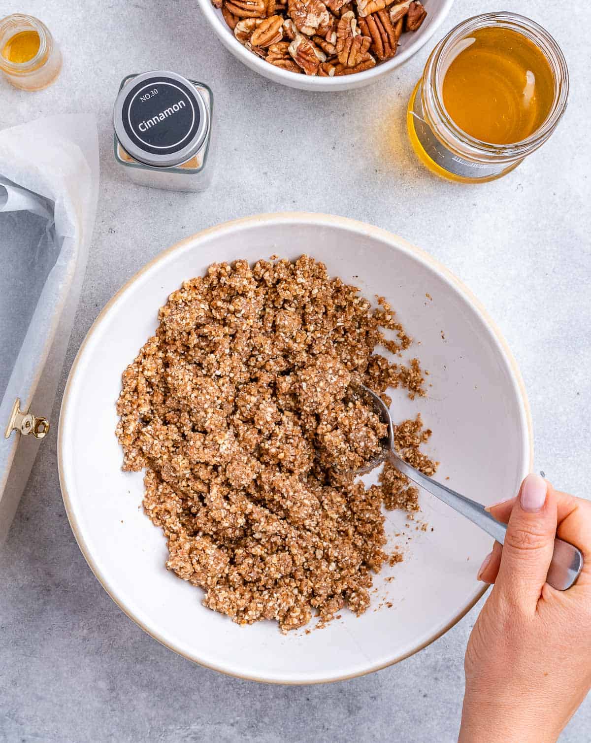 Stirring together almond flour with coconut sugar and honey in a white bowl.