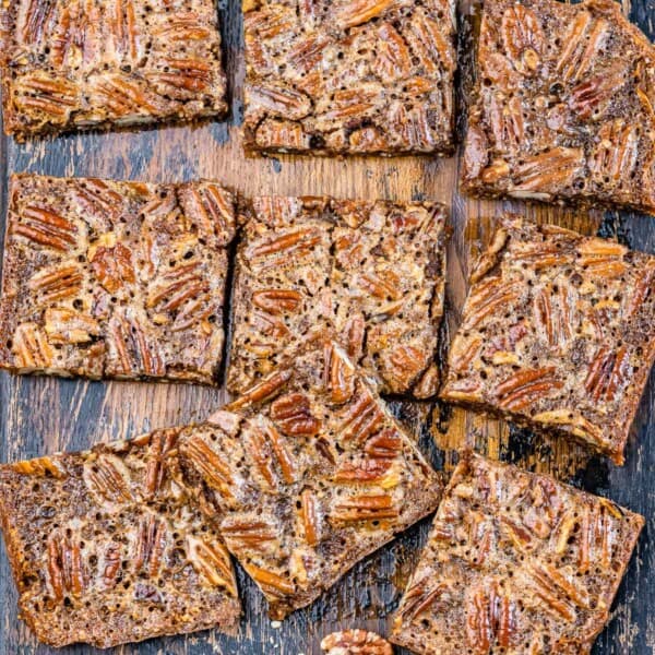 pecan square bars laid out on a dark wood cutting board.