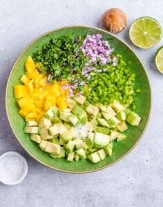 Chopped mango and veggies in a bowl to make salsa.