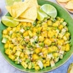 a greed round bowl with mango salad and a few tortilla chips.