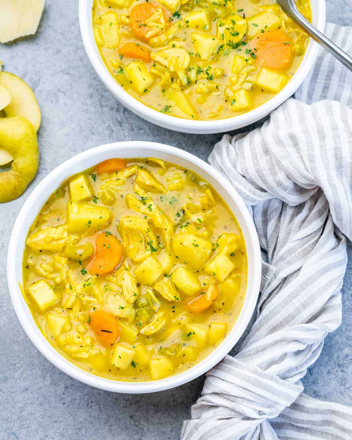 Two white bowls of Mulligatawny soup with a striped cloth.