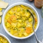 a round bowl of soup with chicken and veggies that's yellow in color.