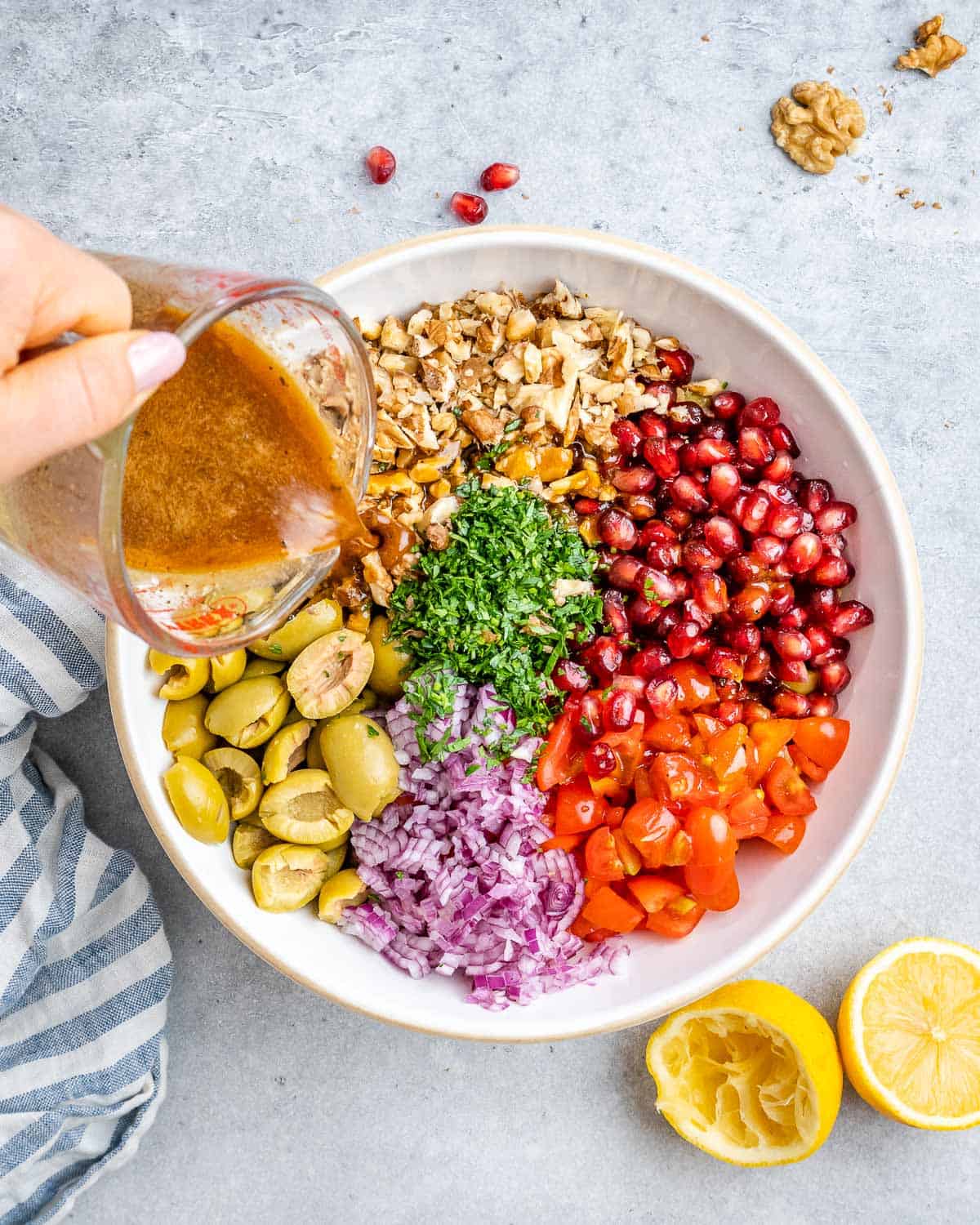Dressing being poured over the salad ingredients in the bowl.