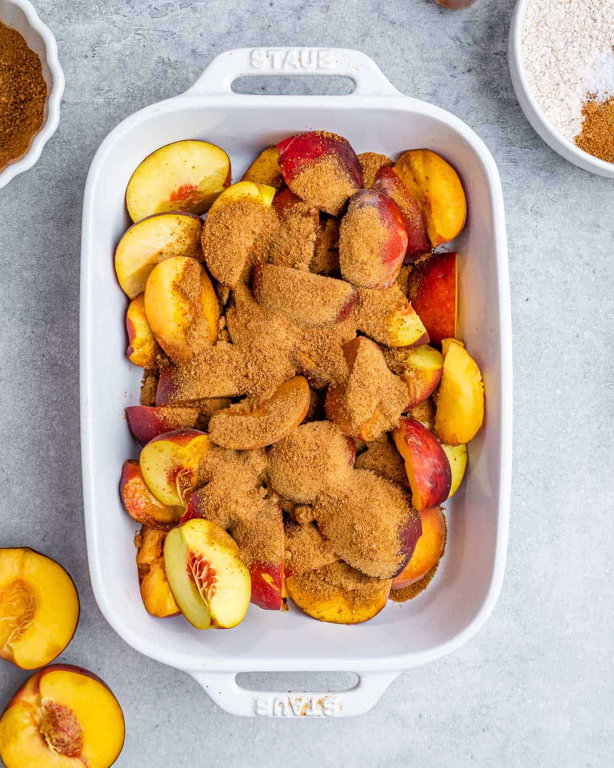 Adding sliced peaches and coconut sugar to a white casserole dish.