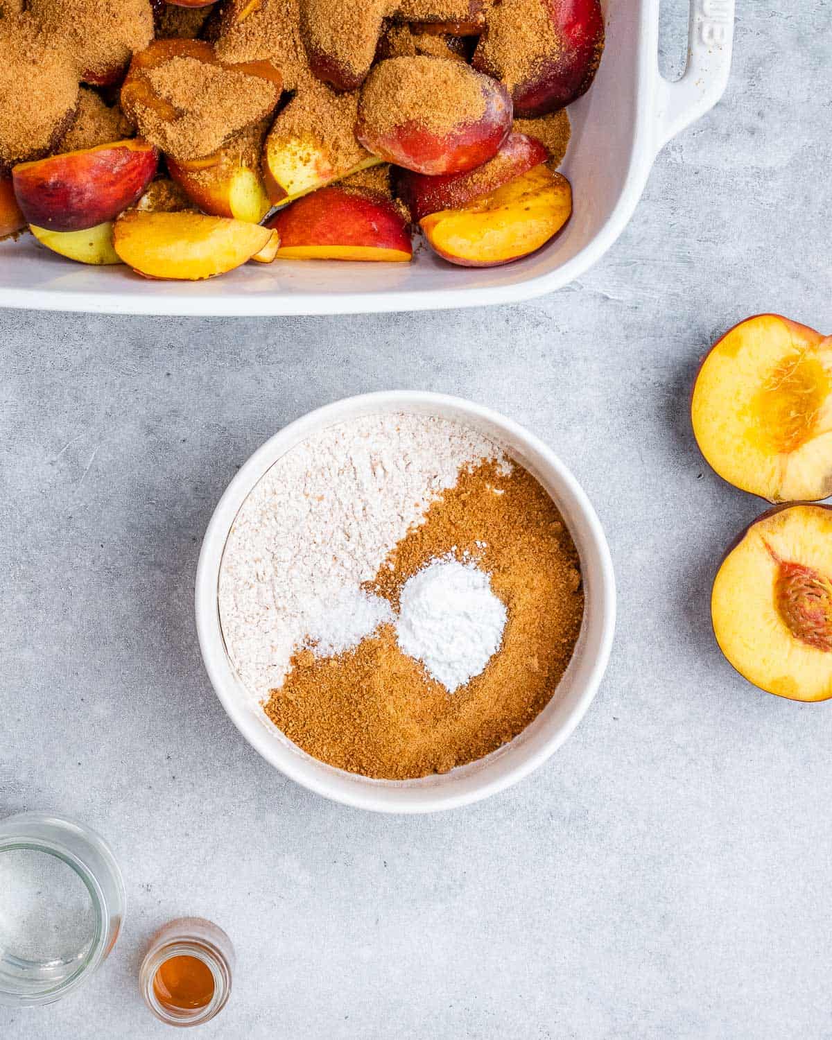 Mixing coconut sugar with flour in a small white bowl near peaches.