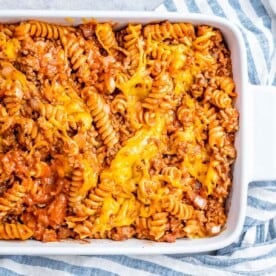 A casserole white dish with rotini pasta in a meaty tomato sauce.