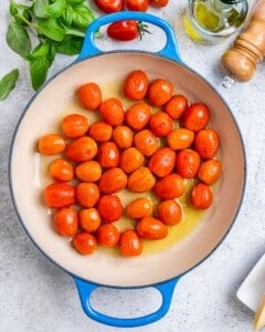 A bowl of fresh cherry tomatoes, washed and ready for cooking.