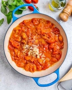 Smashed cherry tomatoes with garlic and parmesan in pan.