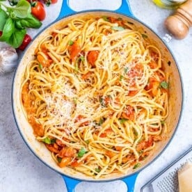 Cooked spaghetti fully coated in tomato basil sauce, ready to serve from a round deep skillet.