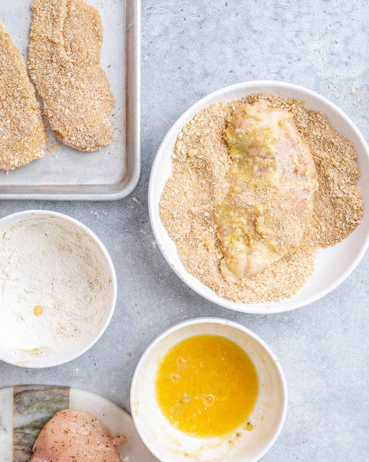 Dredging station with chicken coated in flour and breadcrumbs.